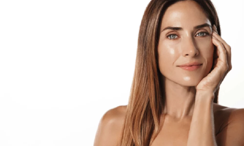 Woman with glowing skin after DiamondGlow, touching her face in Sparta, NJ.